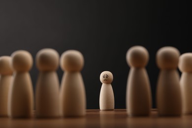 Photo of Loneliness concept. Human figure alone among others on wooden table