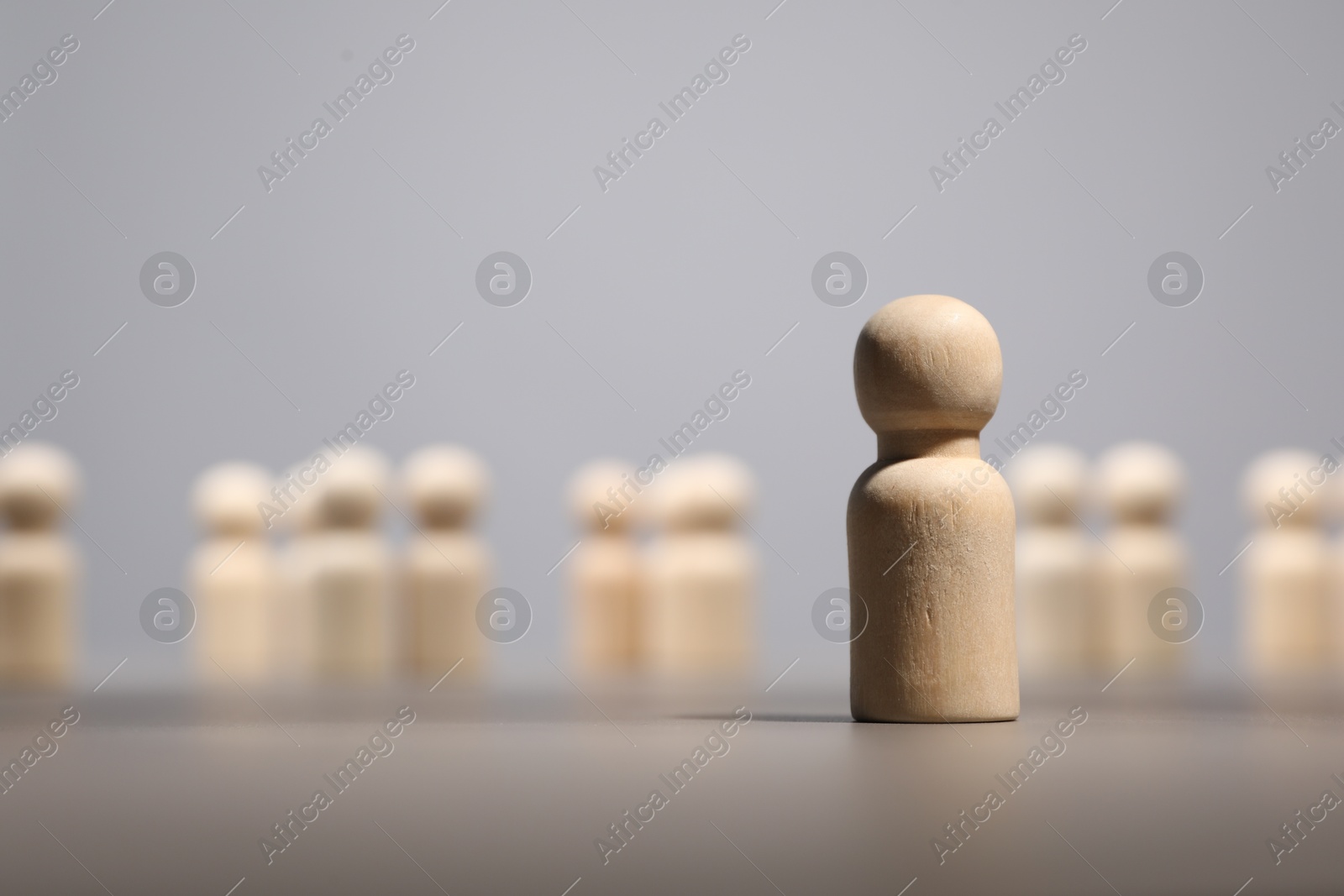 Photo of Loneliness concept. Human figure distant from others on grey background