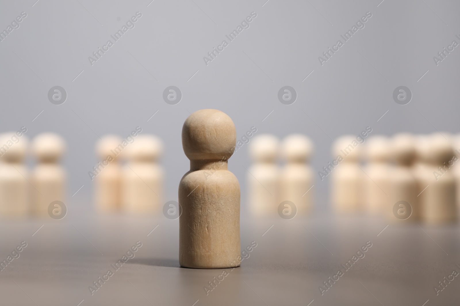 Photo of Loneliness concept. Human figure distant from others on grey background