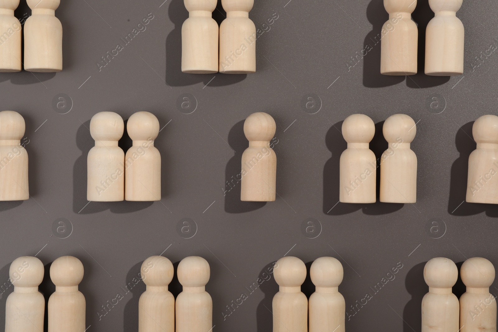 Photo of Loneliness concept. Single human figure among couples on grey background, flat lay