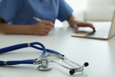 Photo of Doctor at white table in hospital, focus on medical stethoscope