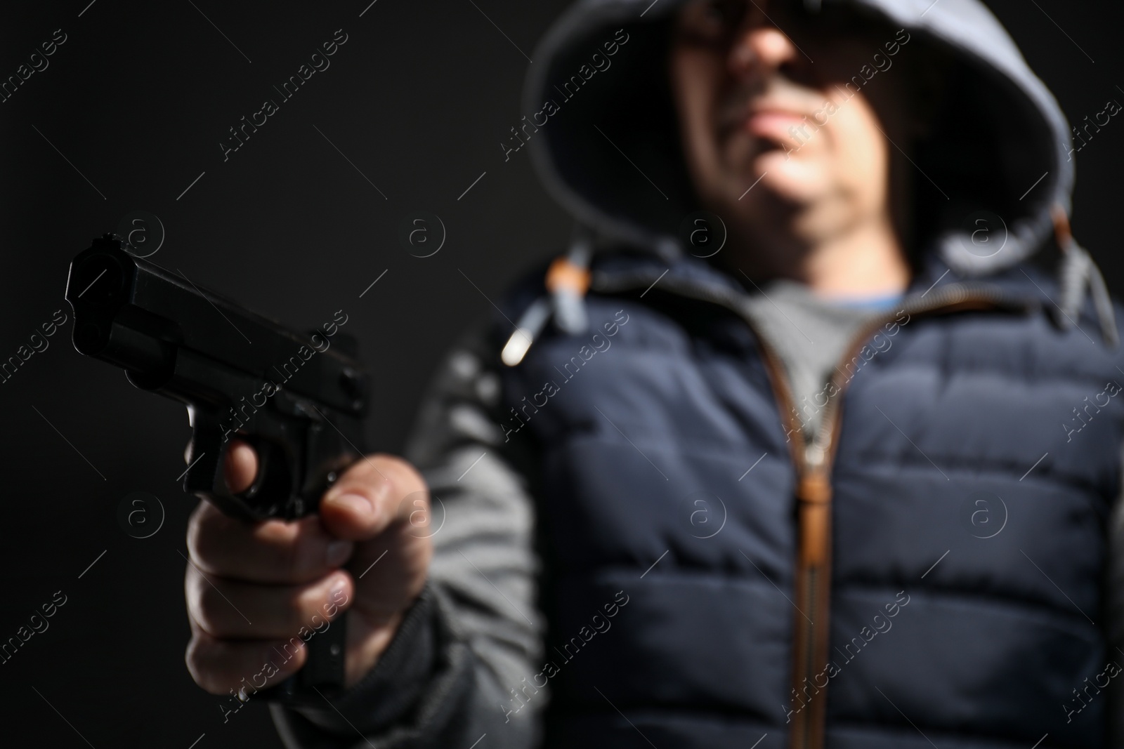 Photo of Dangerous criminal with gun on black background, selective focus. Armed robbery