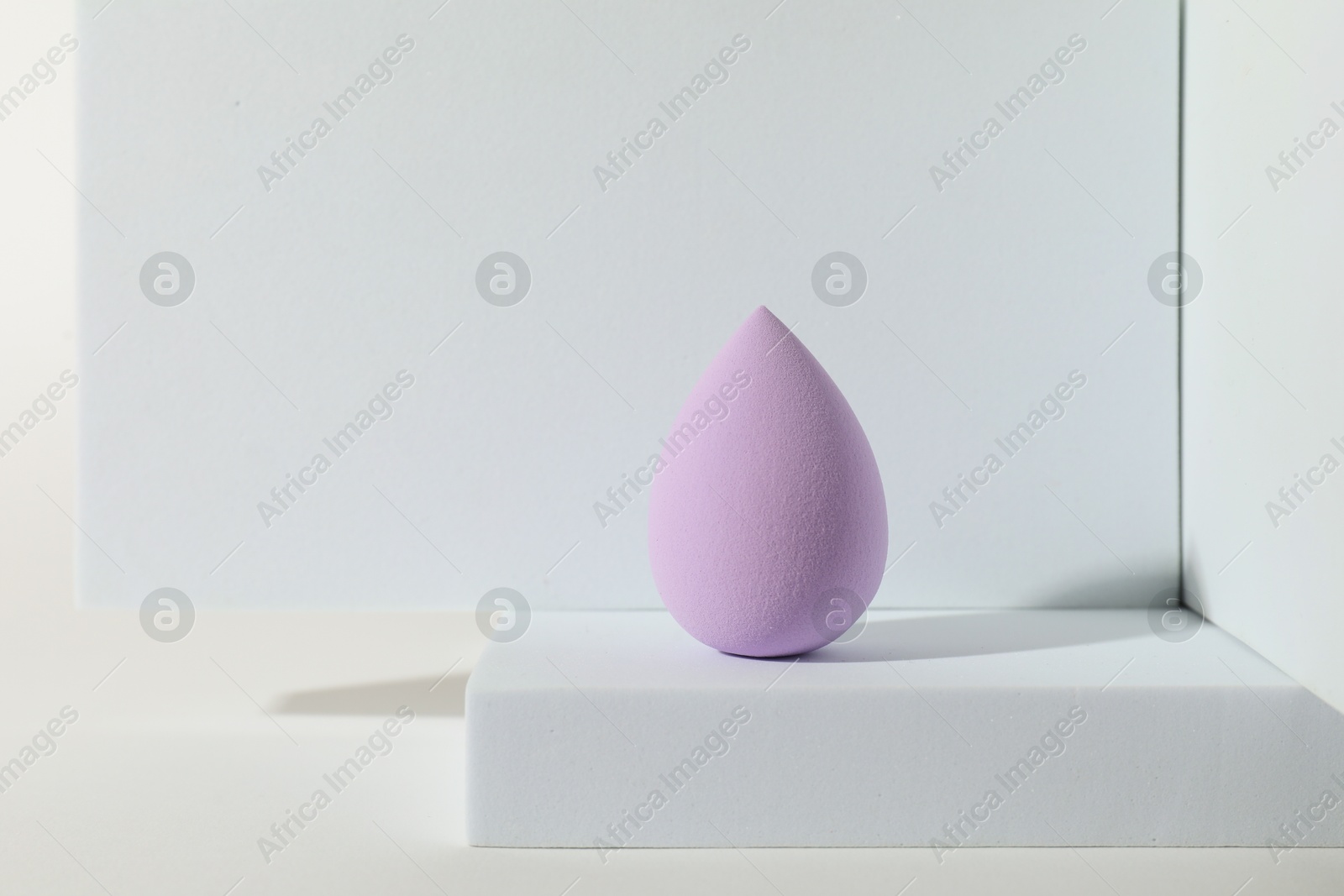 Photo of Stylish presentation of violet makeup sponge on white background