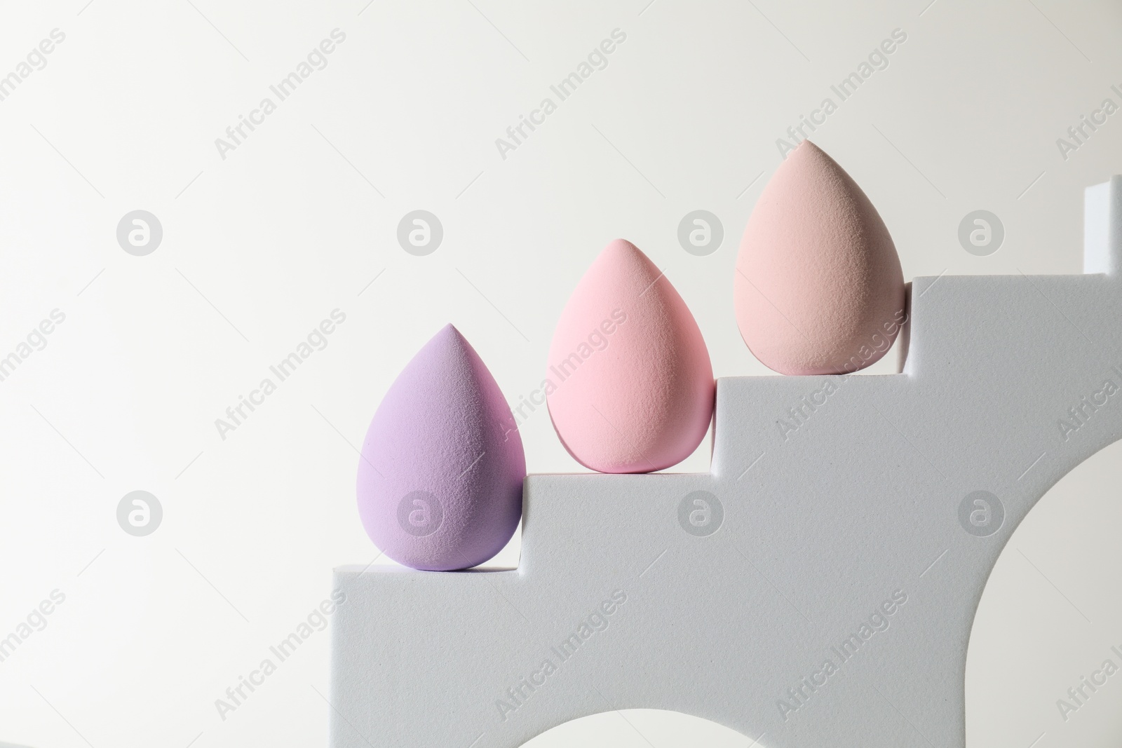 Photo of Stylish presentation of makeup sponges on white background, space for text