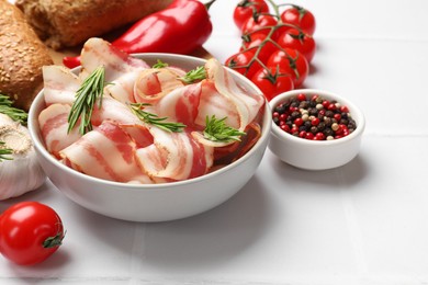 Photo of Slices of raw bacon, spices and tomatoes on white table