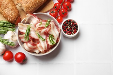 Photo of Slices of raw bacon, spices, bread and tomatoes on white tiled table, flat lay. Space for text