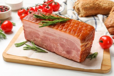 Photo of Piece of raw bacon, rosemary and tomatoes on white table