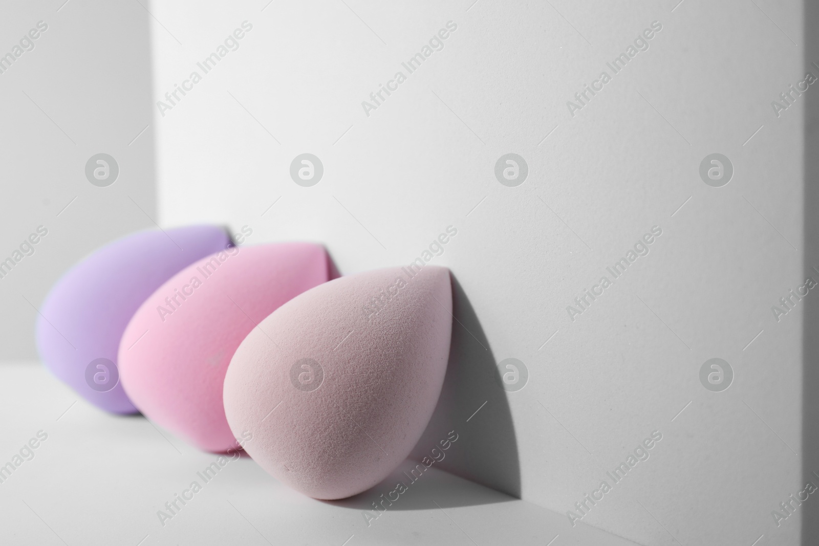 Photo of Stylish presentation of makeup sponges on light grey background. Space for text