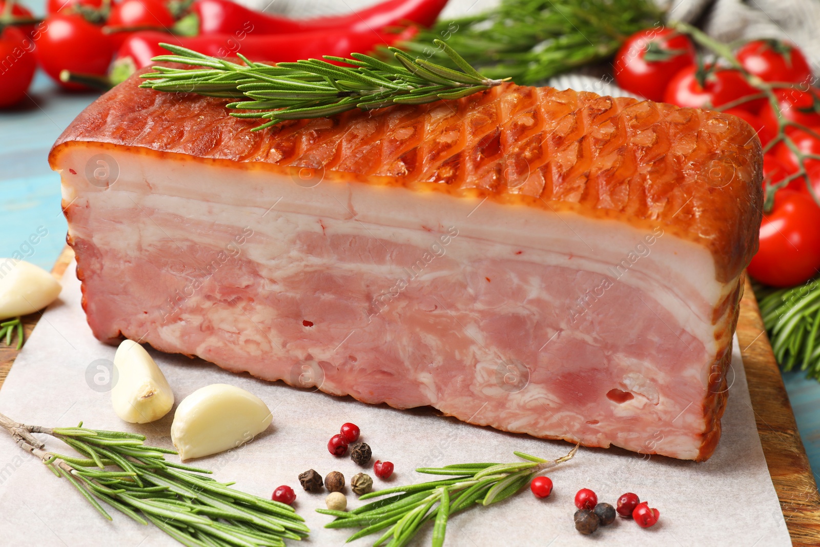 Photo of Piece of raw bacon with spices and cherry tomatoes on light blue table, closeup