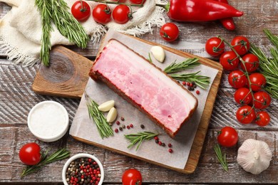 Photo of Piece of raw bacon with spices and cherry tomatoes on wooden table, flat lay