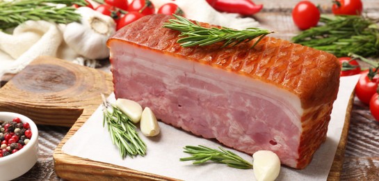 Photo of Piece of raw bacon with spices and cherry tomatoes on wooden table, closeup. Banner design