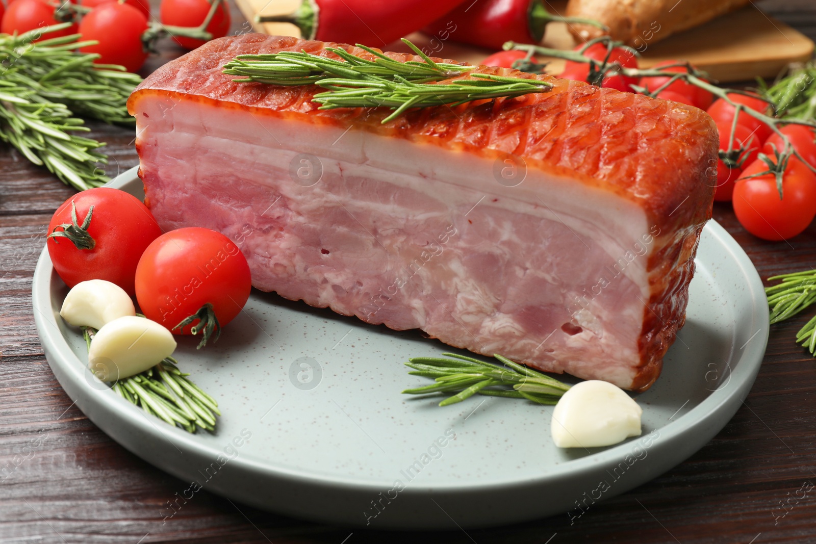 Photo of Piece of raw bacon with spices and cherry tomatoes on wooden table, closeup