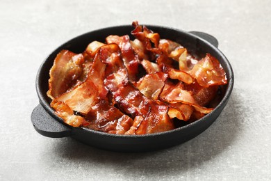 Photo of Delicious bacon slices in frying pan on light grey table