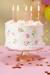 Tasty Birthday cake with burning candles and confetti on pink table