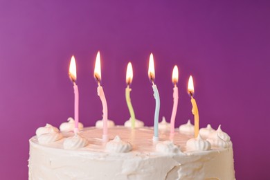 Tasty Birthday cake with burning candles against purple background, closeup