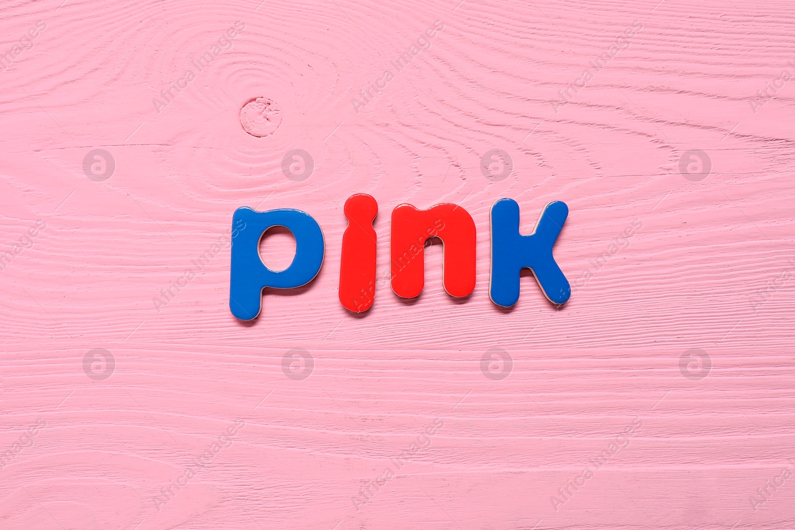 Photo of Word Pink made of magnetic letters on bright wooden background, top view. Learning alphabet