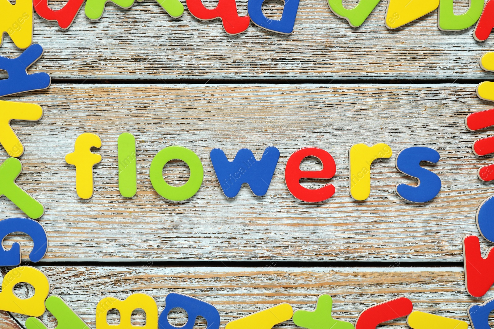 Photo of Word Flowers made of magnetic letters on wooden background, flat lay. Learning alphabet