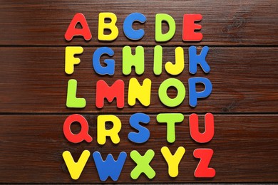 Alphabetical order. Bright magnetic letters on wooden background, top view