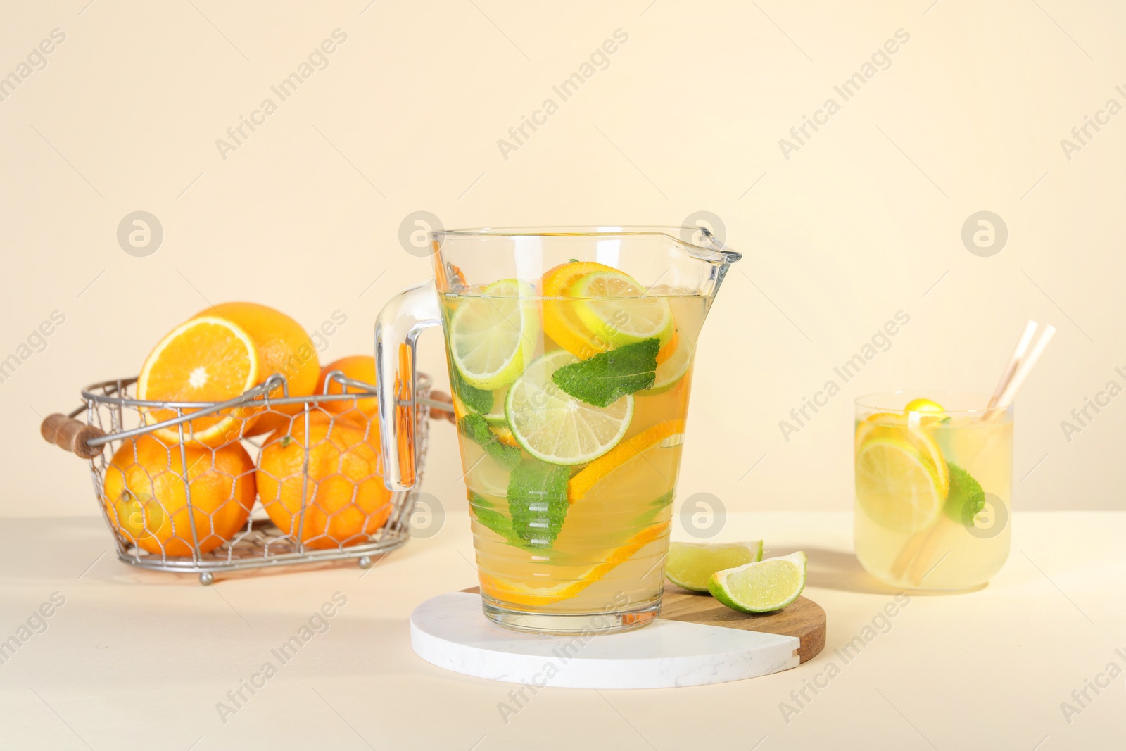 Photo of Freshly made lemonade with mint in jug and glass on beige background