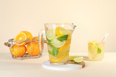 Photo of Freshly made lemonade with mint in jug and glass on beige background