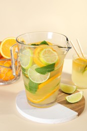 Photo of Freshly made lemonade with mint in jug and glass on beige background