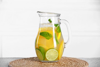 Photo of Freshly made lemonade with mint in jug on light grey table