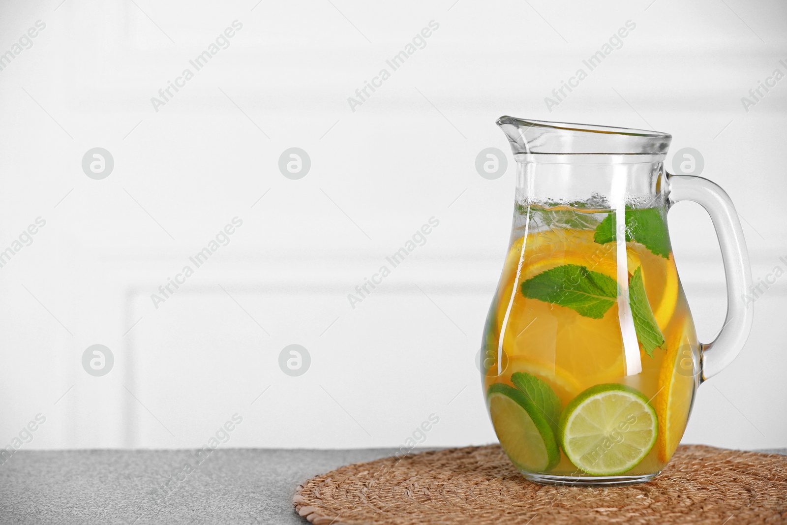 Photo of Freshly made lemonade with mint in jug on light grey table, space for text