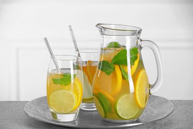 Photo of Freshly made lemonade with mint in jug and glasses on light grey table