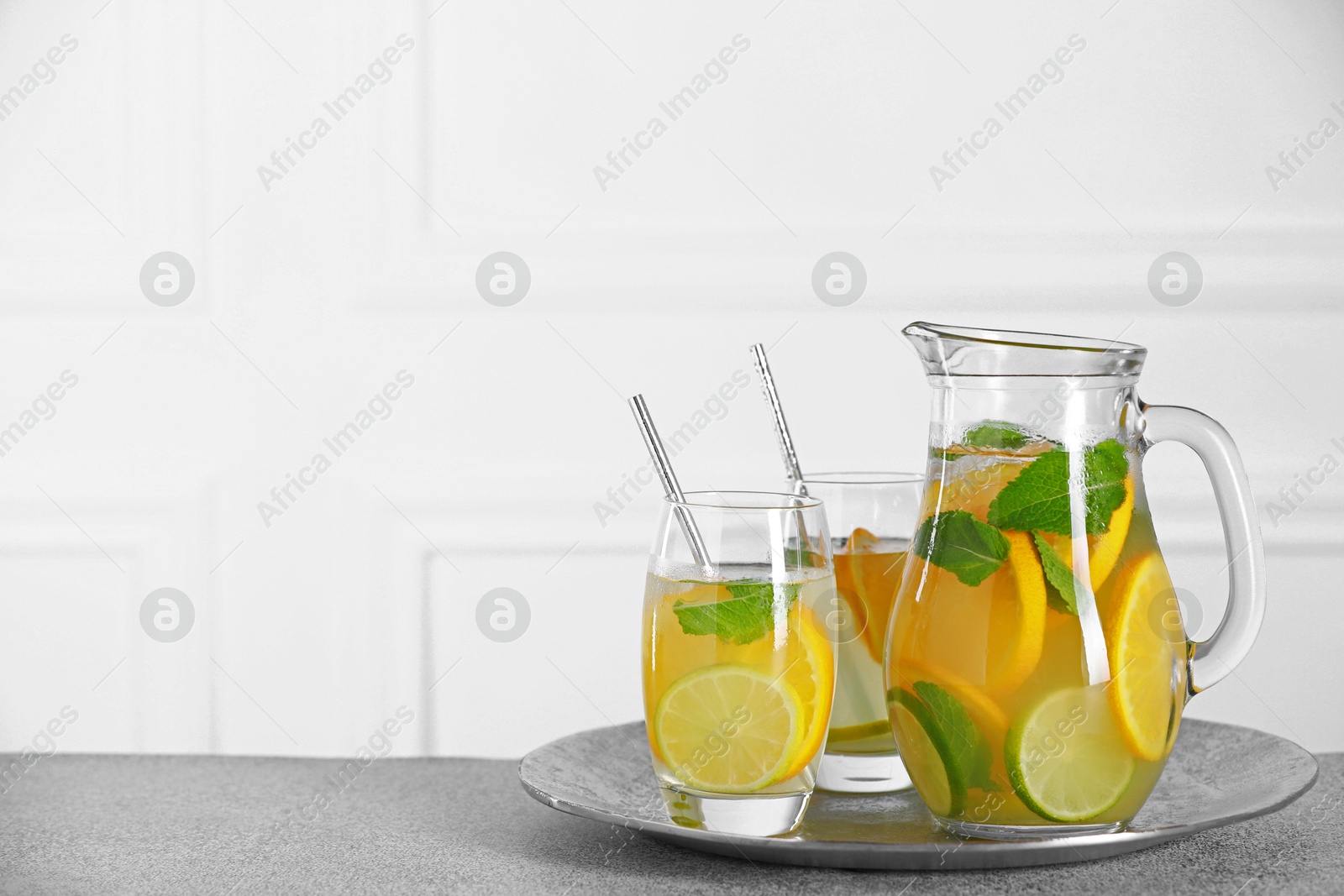 Photo of Freshly made lemonade with mint in jug and glasses on light grey table, space for text