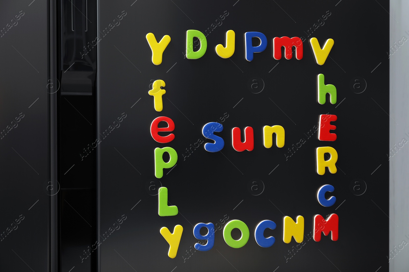 Photo of Word Sun and frame made of many bright magnetic letters on fridge indoors. Learning alphabet