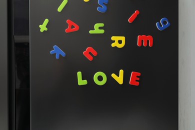 Word Love made of many bright magnetic letters on fridge indoors. Learning alphabet