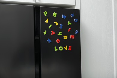 Photo of Word Love made of many bright magnetic letters on fridge indoors. Learning alphabet