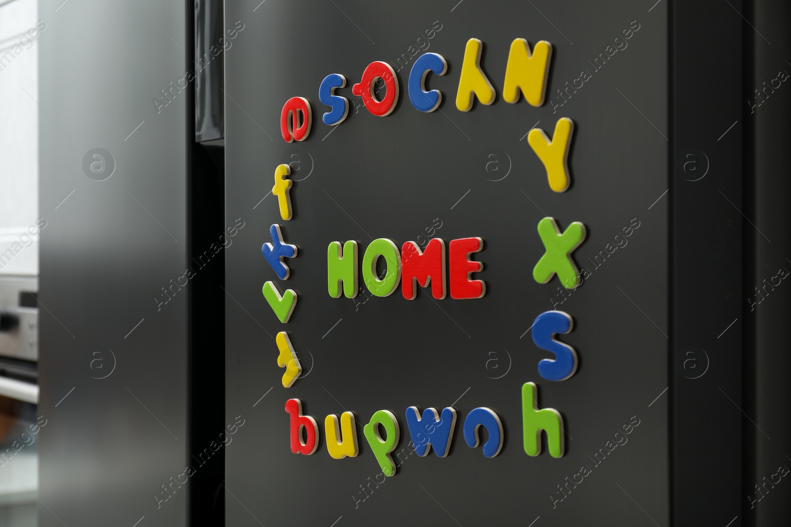 Photo of Word Home and frame made of many bright magnetic letters on fridge indoors. Learning alphabet