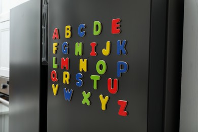 Alphabetical order. Many bright magnetic letters on fridge indoors