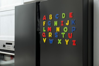 Alphabetical order. Many bright magnetic letters on fridge indoors