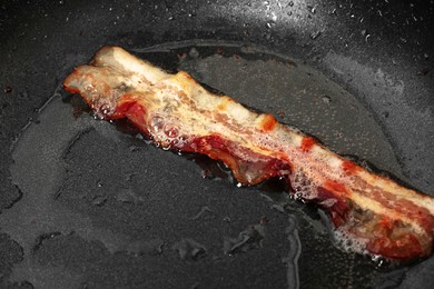 Photo of One slice of bacon frying in pan, closeup