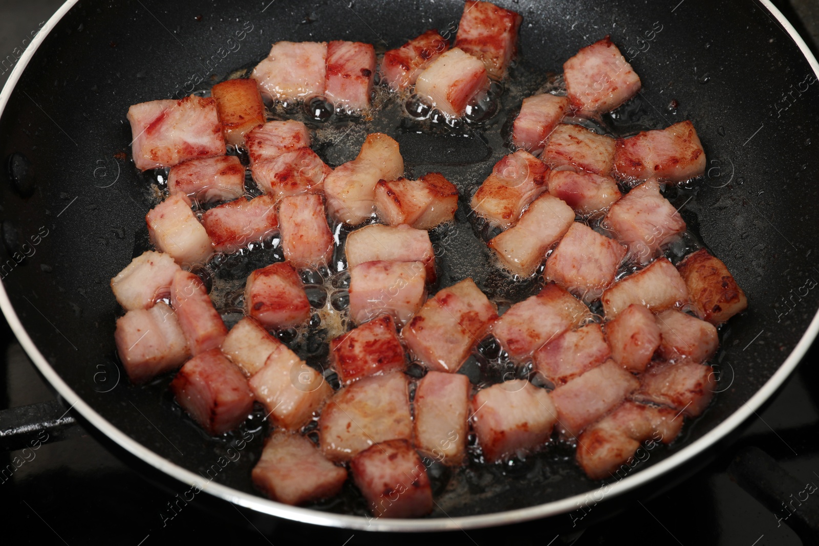 Photo of Pieces of bacon frying in pan, closeup