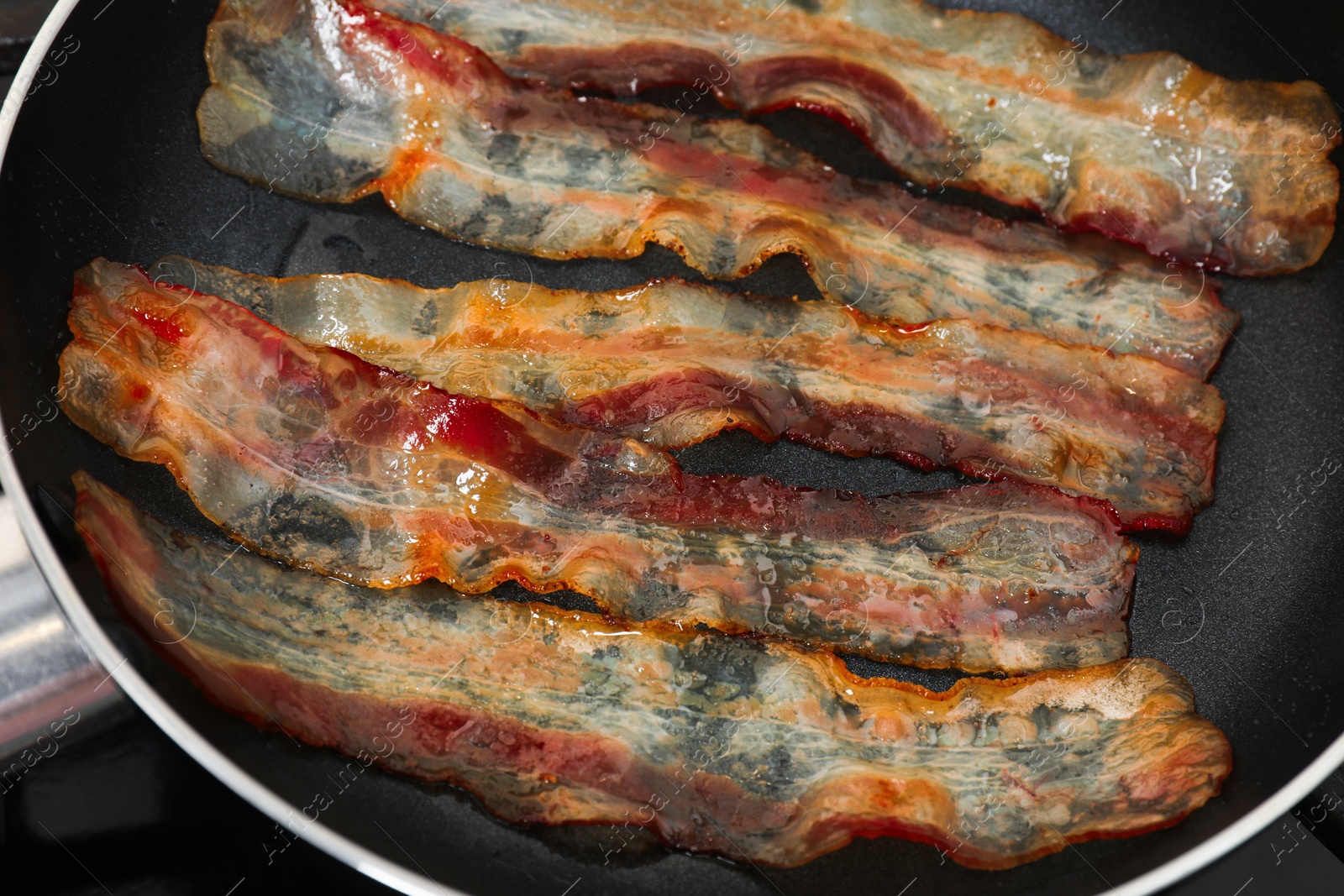 Photo of Slices of bacon frying in pan, closeup