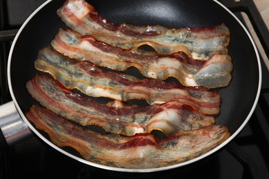 Slices of bacon frying in pan, closeup