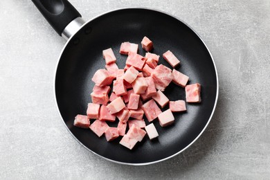 Photo of Pieces of fresh bacon in frying pan on grey textured table, top view