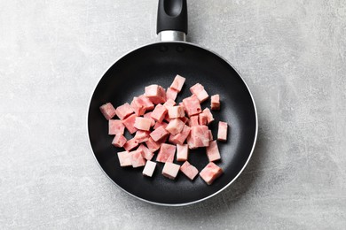 Photo of Pieces of fresh bacon in frying pan on grey textured table, top view