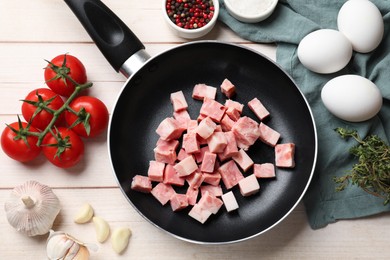 Photo of Pieces of fresh bacon in frying pan and products on light wooden table, flat lay