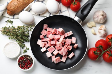 Photo of Pieces of fresh bacon in frying pan and products on white table, flat lay