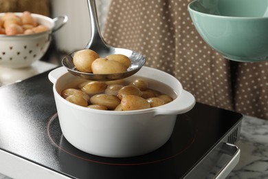 Photo of Taking potatoes from pot on stove, closeup