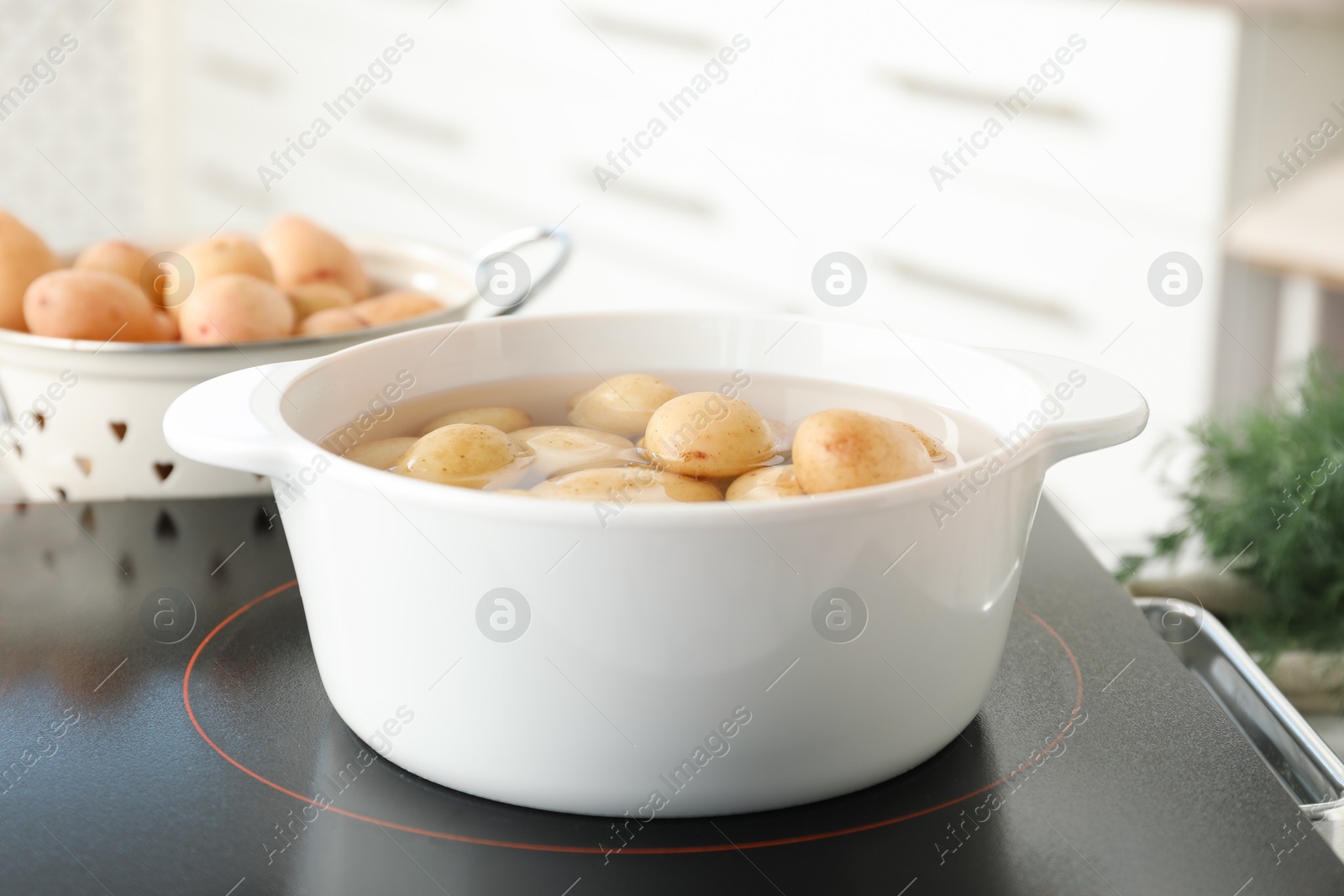 Photo of Boiling potatoes in pot on stove in kitchen