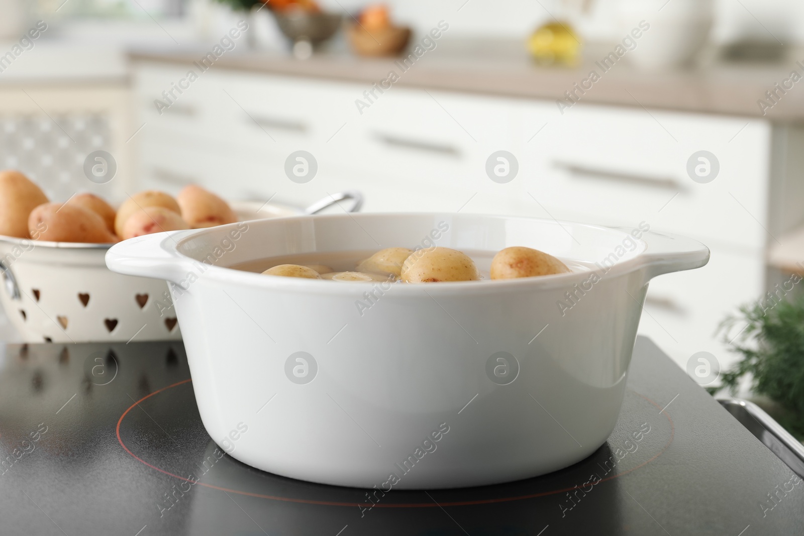 Photo of Boiling potatoes in pot on stove in kitchen