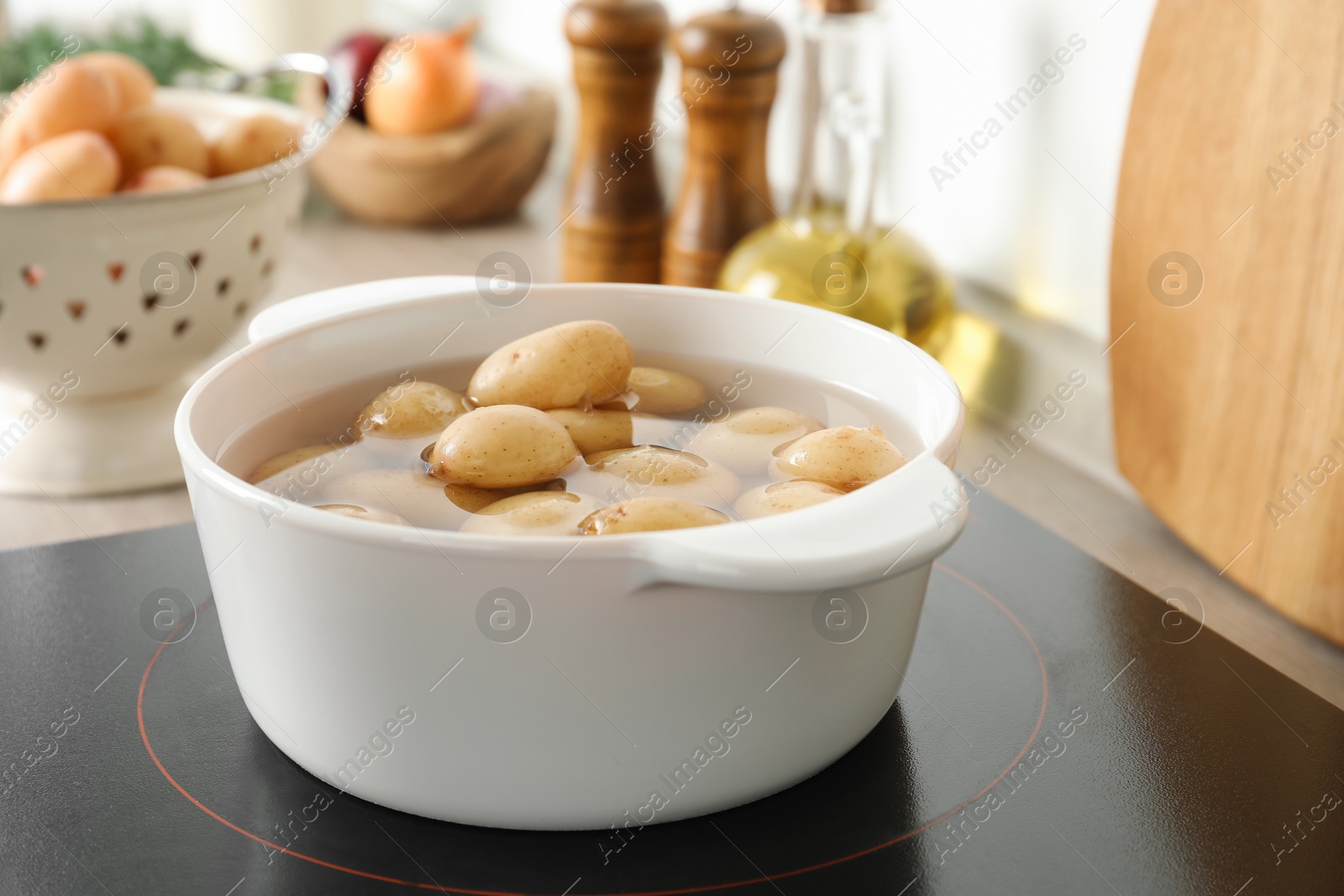 Photo of Boiling potatoes in pot on stove in kitchen