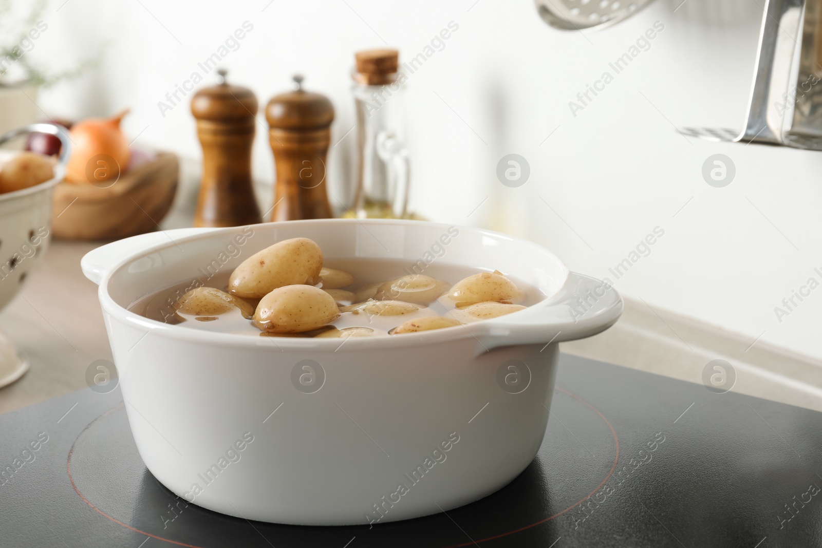 Photo of Boiling potatoes in pot on stove in kitchen