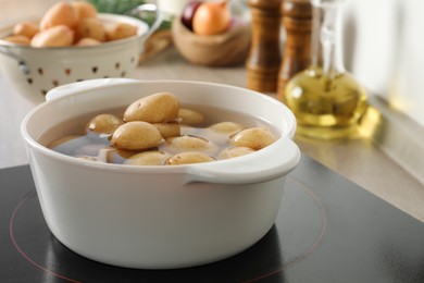 Photo of Boiling potatoes in pot on stove in kitchen