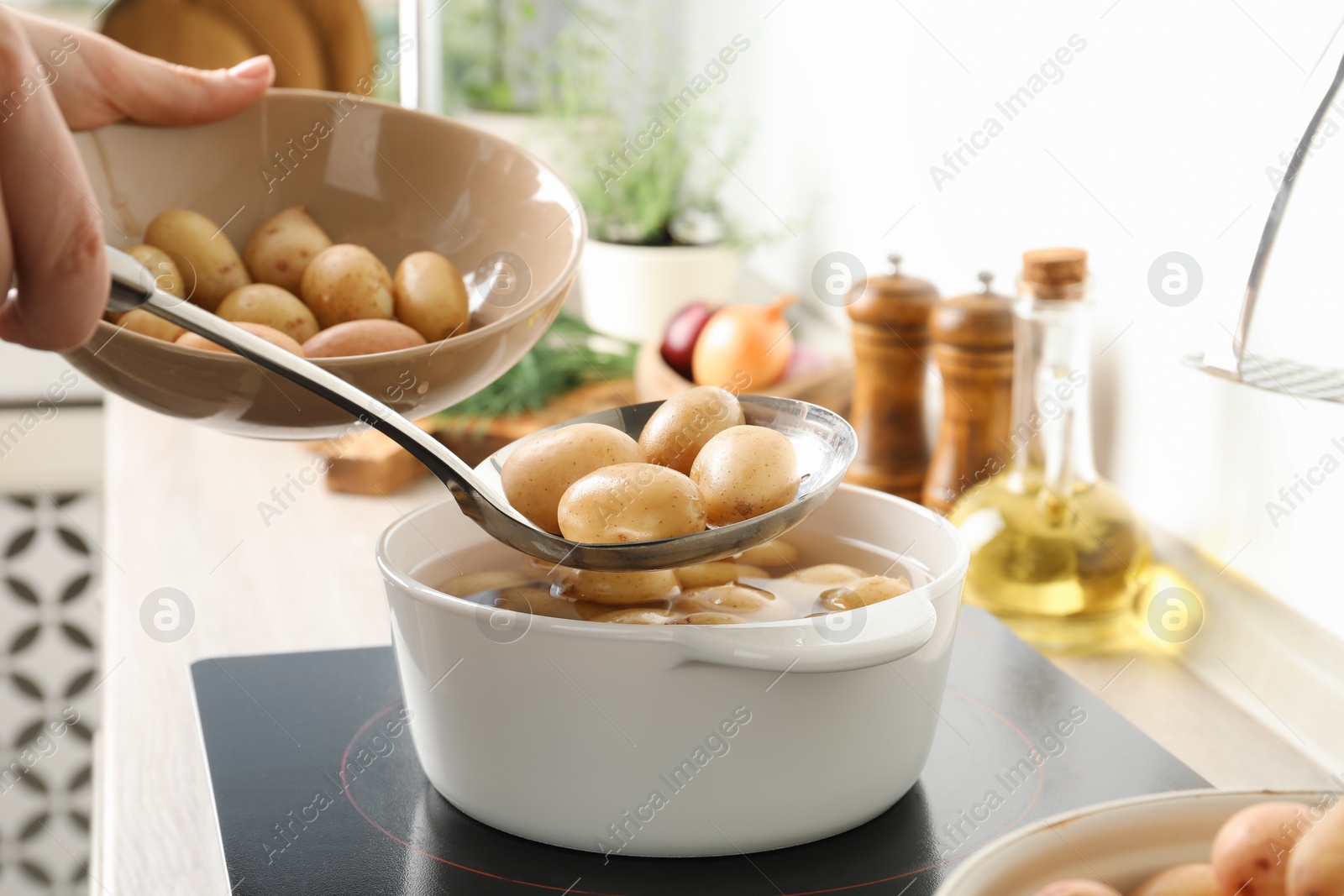 Photo of Woman taking potatoes from pot on stove, closeup